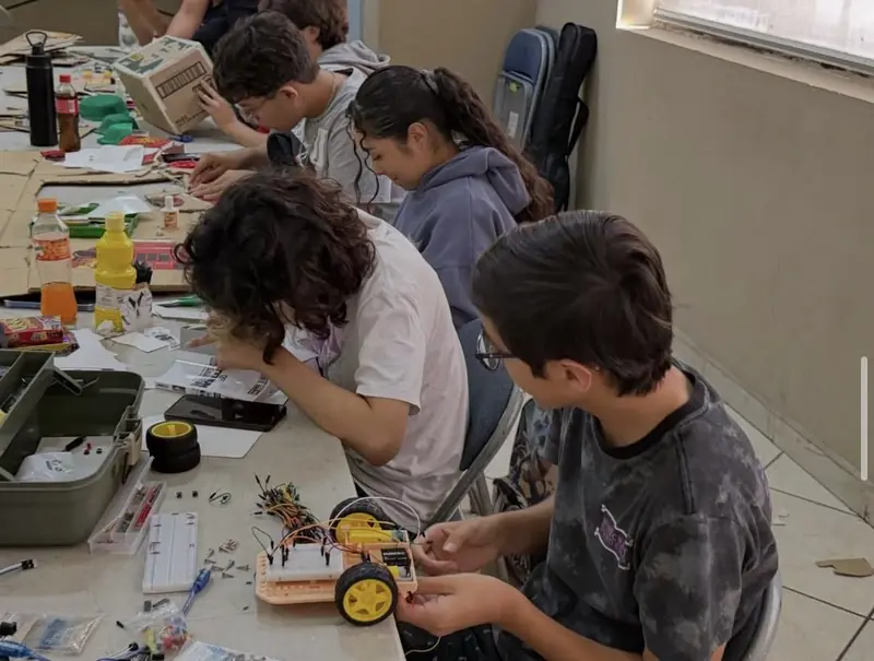 Estudiantes armando juntos un carro robot en un taller Qubiko
